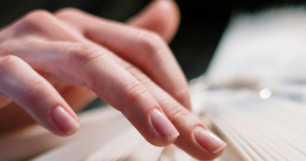 Close-up of a woman's hand selecting nail polish colors in a beauty salon.