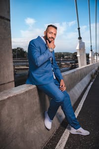 Foto de Jrfotosgrand Fotografia Confident man in blue suit poses on a bridge, exuding modern fashion and elegance.